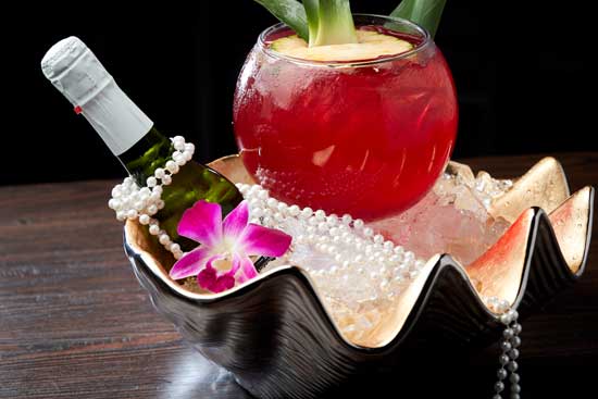 Specialty drink on large oyster shaped bowl with champagne bottle